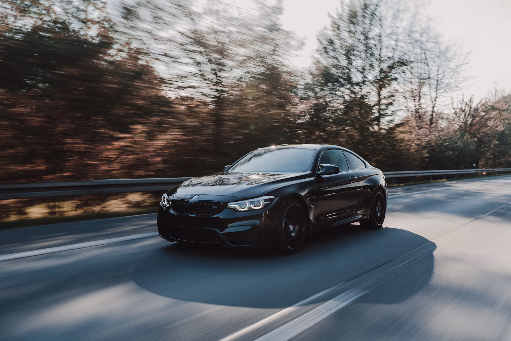 Black BMW coupé on an autumn road